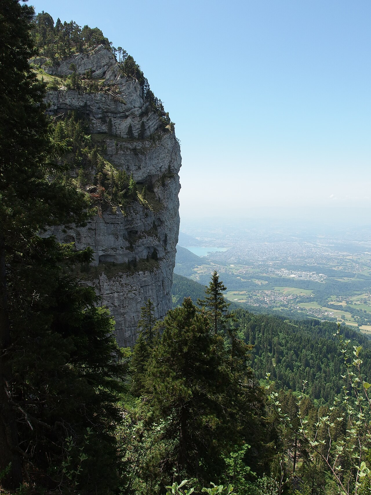 Vue depuis la Tête du Parmelan avec sa croix sommitale et le refuge Camille Dunant surplombant Annecy, massif des Bornes, Haute-Savoie